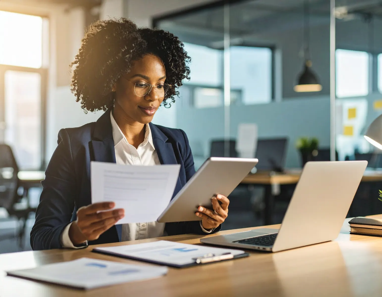 Businesswoman reviewing documents and a tablet at her desk